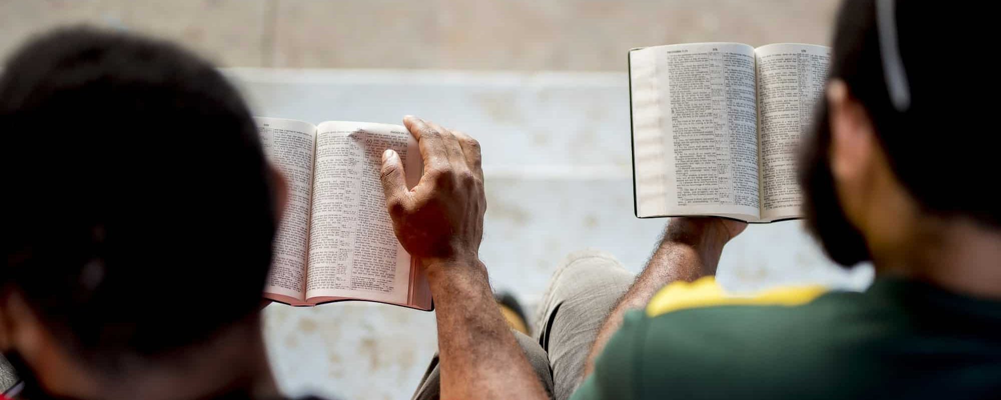 Overhead shot of people sitting and reading the bible with a blurred background