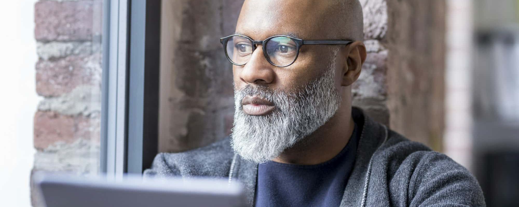 Portrait of pensive man with tablet looking out of window